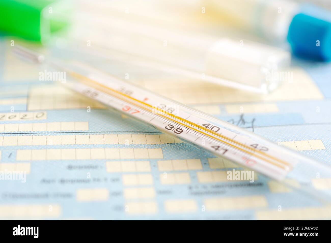 termometro su un tavolo sullo sfondo di un documento medico. un sintomo di un coronavirus o influenza Foto Stock