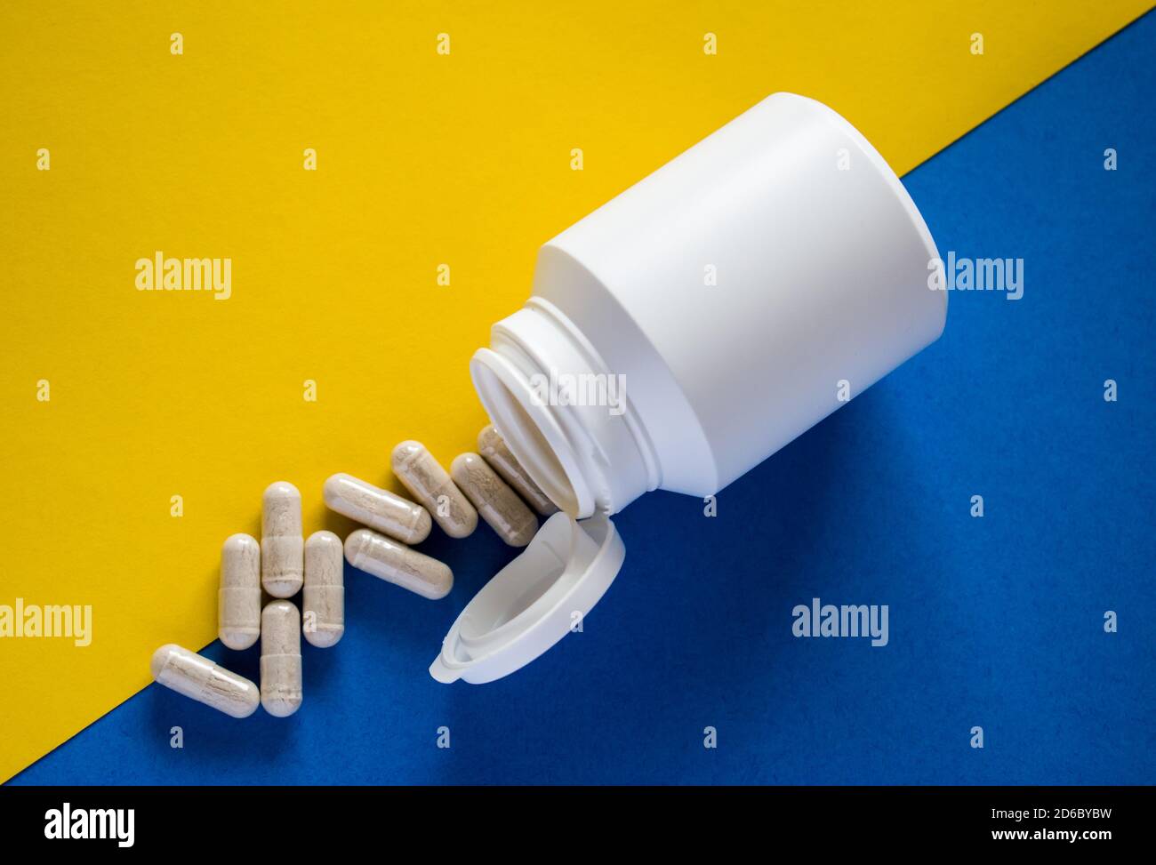 Pillole mediche bianche con scatola di pillola su giallo e blu sfondo Foto Stock