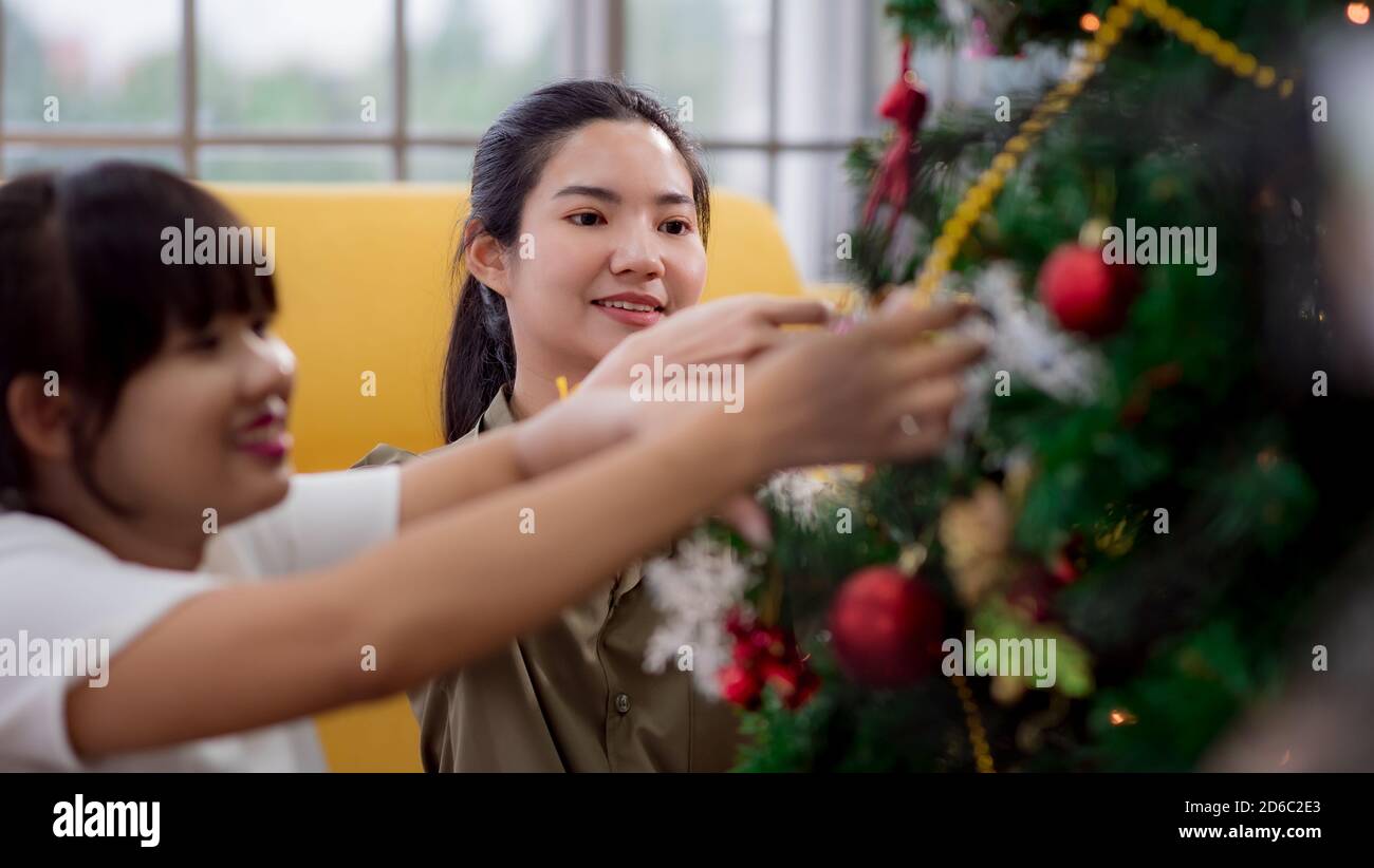 Giovane donna asiatica che decora un albero di Natale Foto Stock