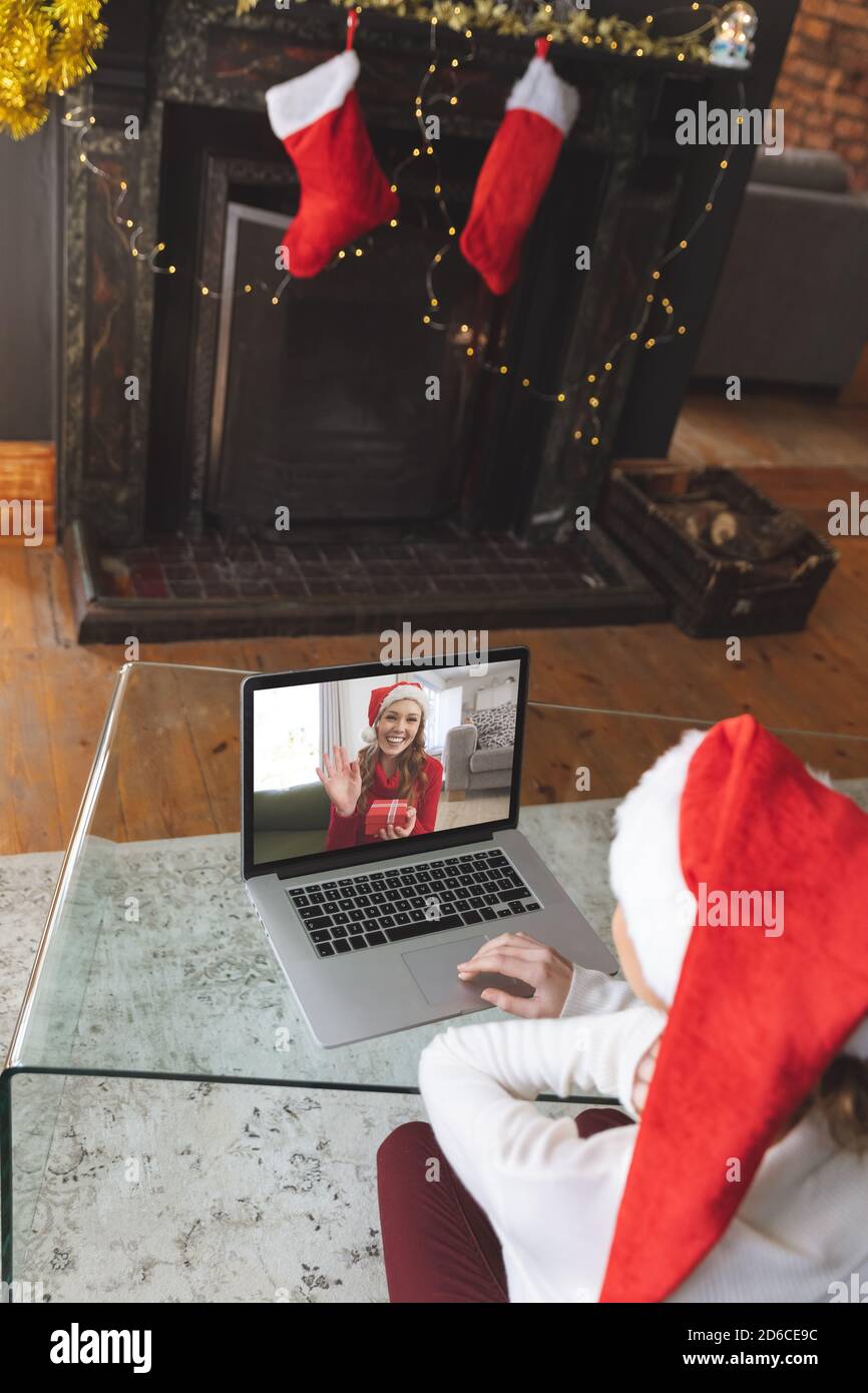 Donna in cappello di Santa che ha una video chat con un altro donna su un computer portatile a casa Foto Stock