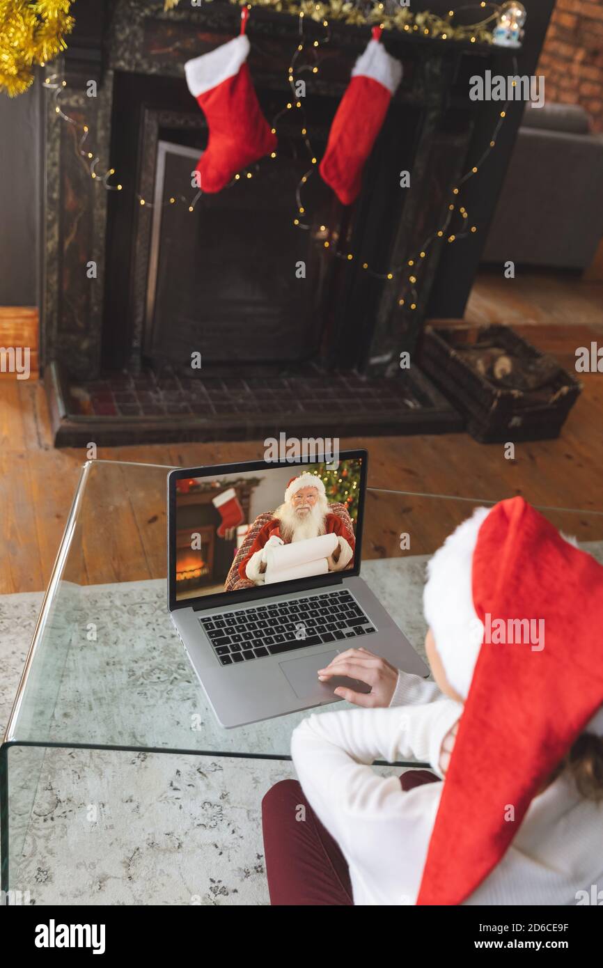 Donna in cappello di Santa che ha una video chat con Santa Claus su un computer portatile a casa Foto Stock