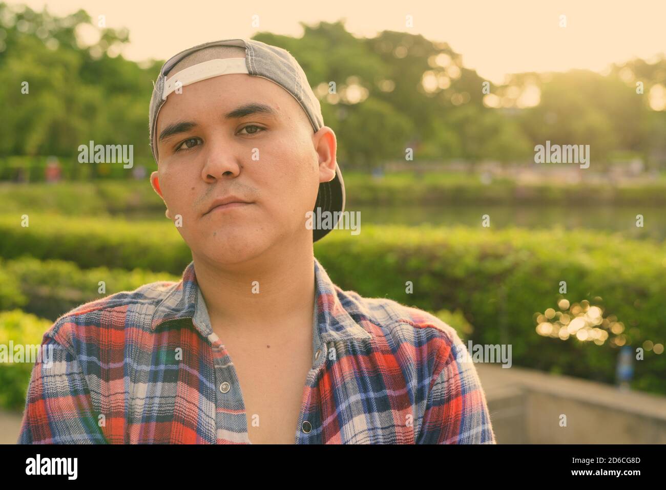 Giovane asiatico che indossa il cappello mentre si rilassa nel parco di Bangkok, Thailandia Foto Stock