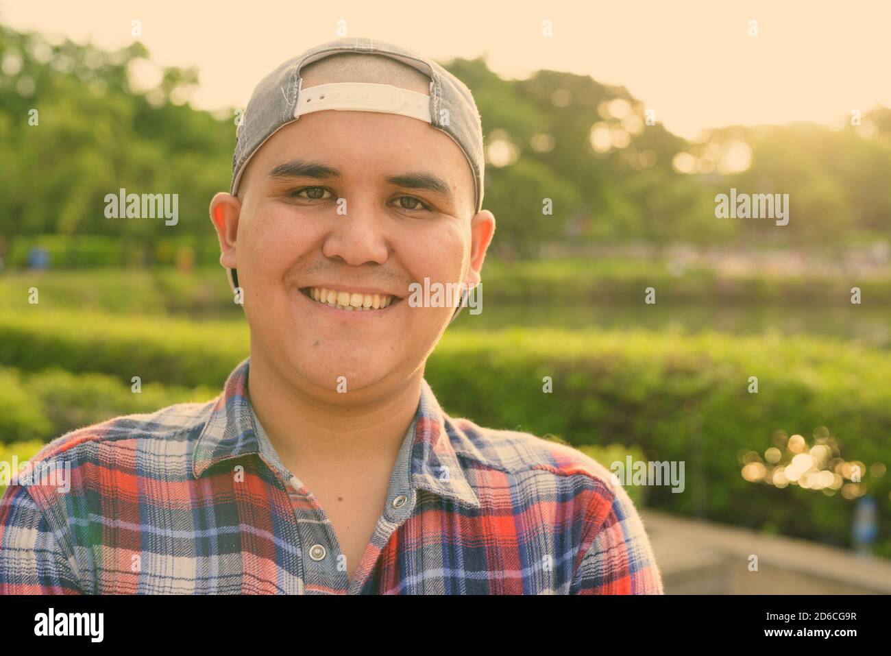 Giovane asiatico che indossa il cappello mentre si rilassa nel parco di Bangkok, Thailandia Foto Stock