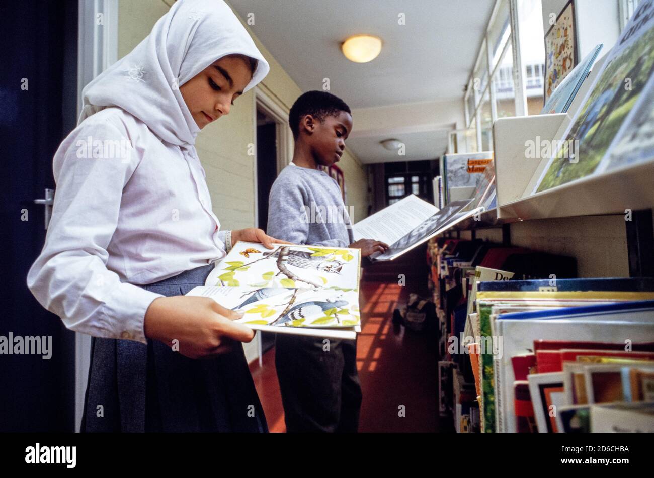 Gli studenti navigano nei libri della biblioteca della scuola elementare Christchurch CoFe di Londra NW1. 02 luglio 1991. Foto: Neil Turner Foto Stock