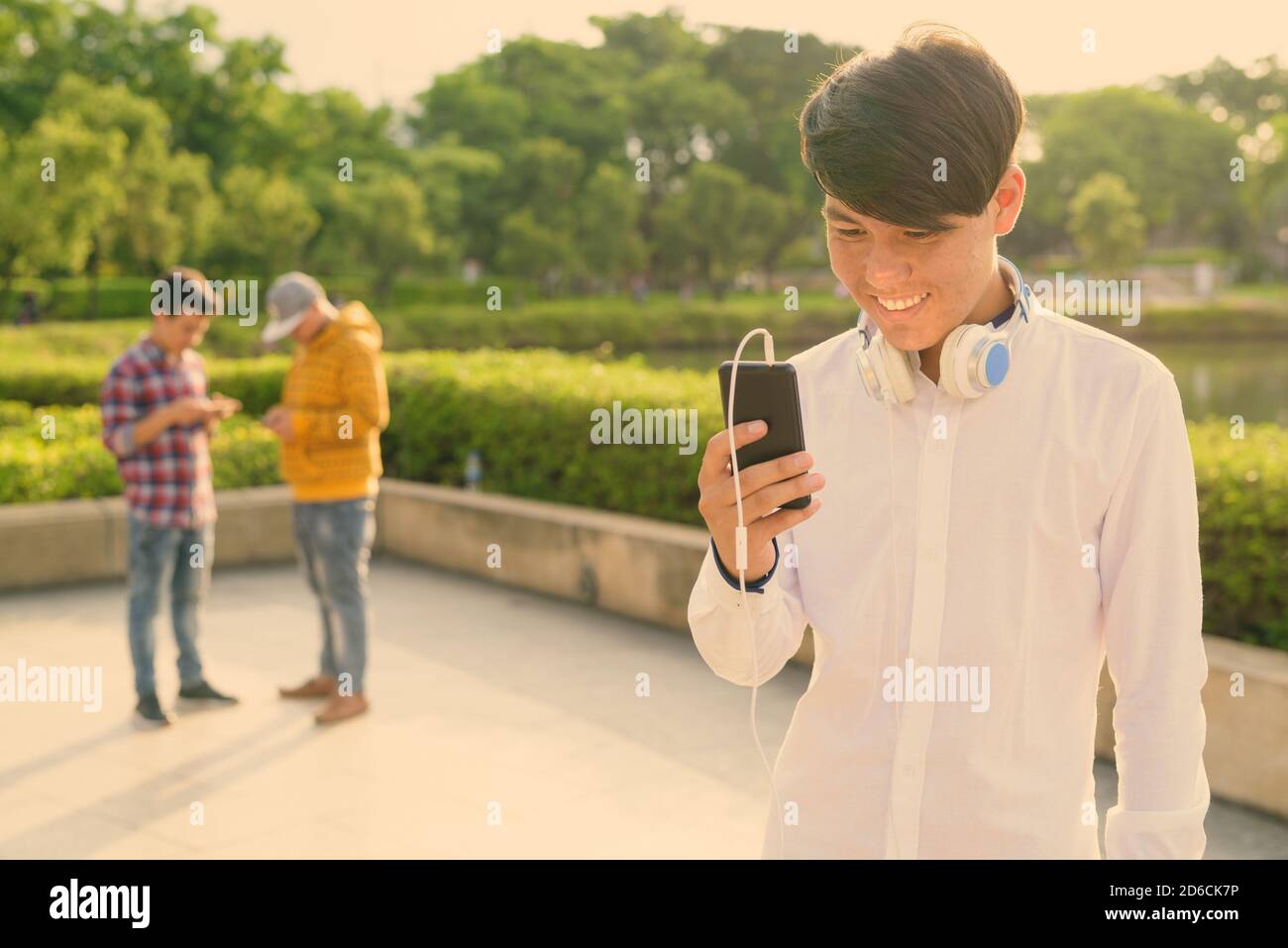 Tre giovani uomini asiatici di relax presso il parco insieme Foto Stock