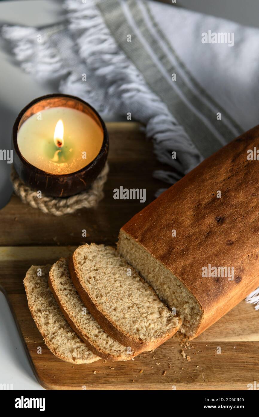 Pane fatto in casa a fette su un tagliere di legno con un candela su un tovagliolo bianco Foto Stock