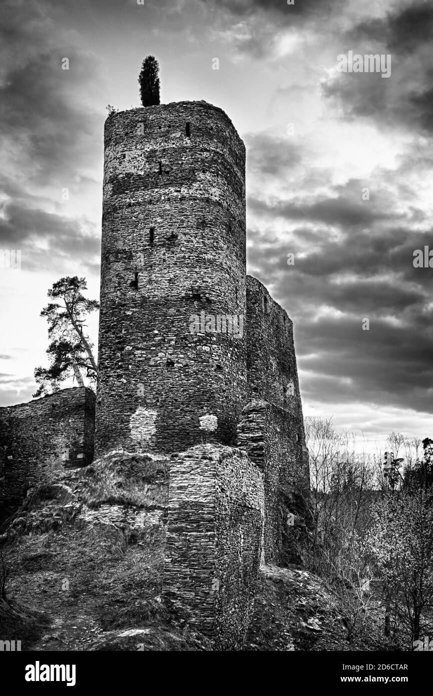 Bella caszle medievale ceco Gutstejn situato sulla roccia sopra il fiume nella Boemia occidentale, girato al tramonto in monocromia. HDR Foto Stock