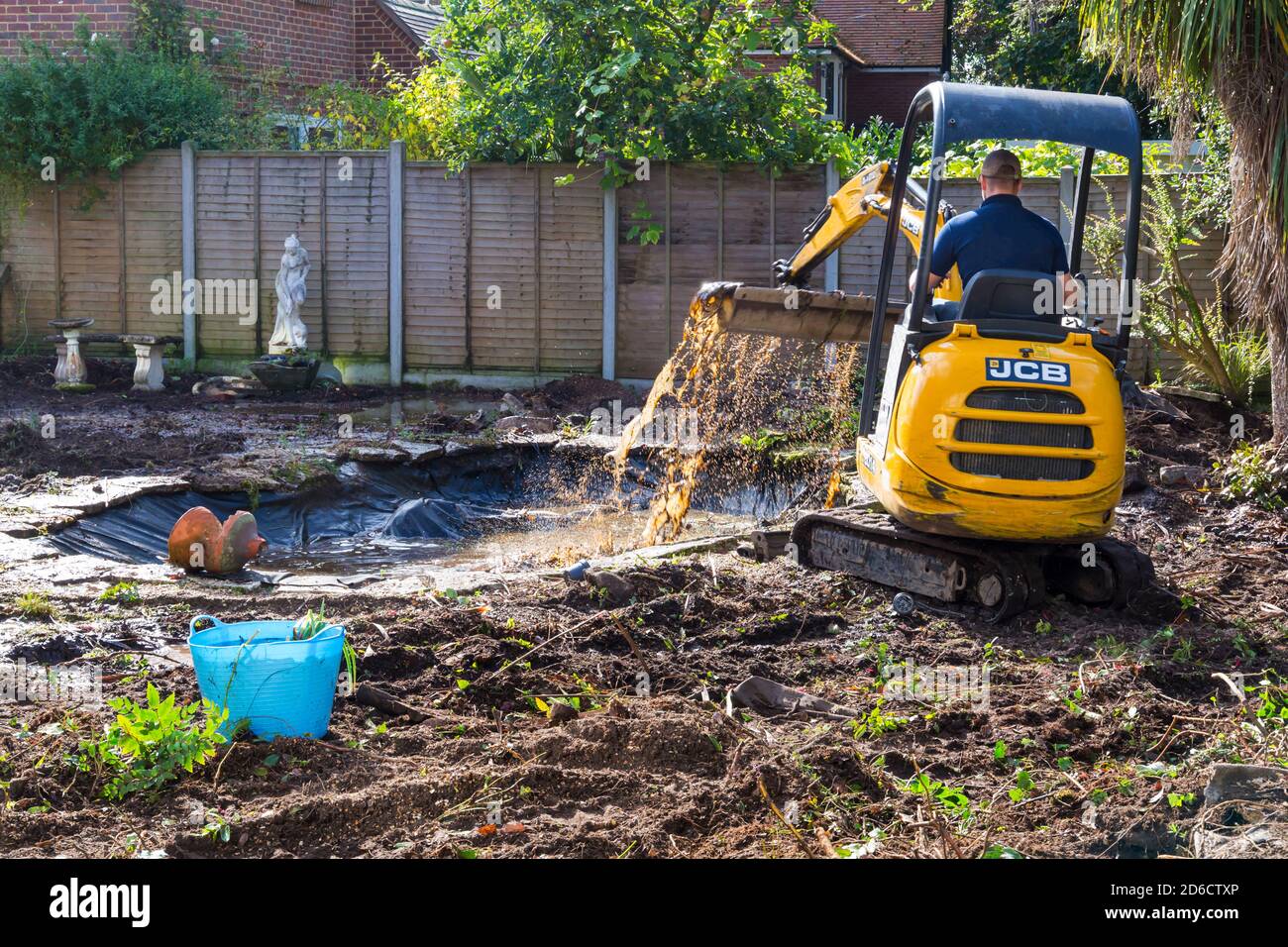 Lavori di sdoganamento e ristrutturazione del giardino che prendono parte al giardino a Bournemouth, Dorset UK nel mese di ottobre - giardino di sdoganamento con mini scavatore jcb Foto Stock