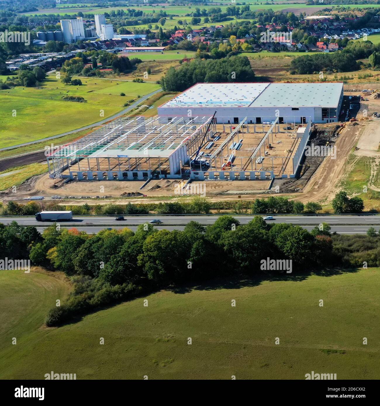 Vista aerea di un cantiere con il guscio di un magazzino vicino a una superstrada Foto Stock