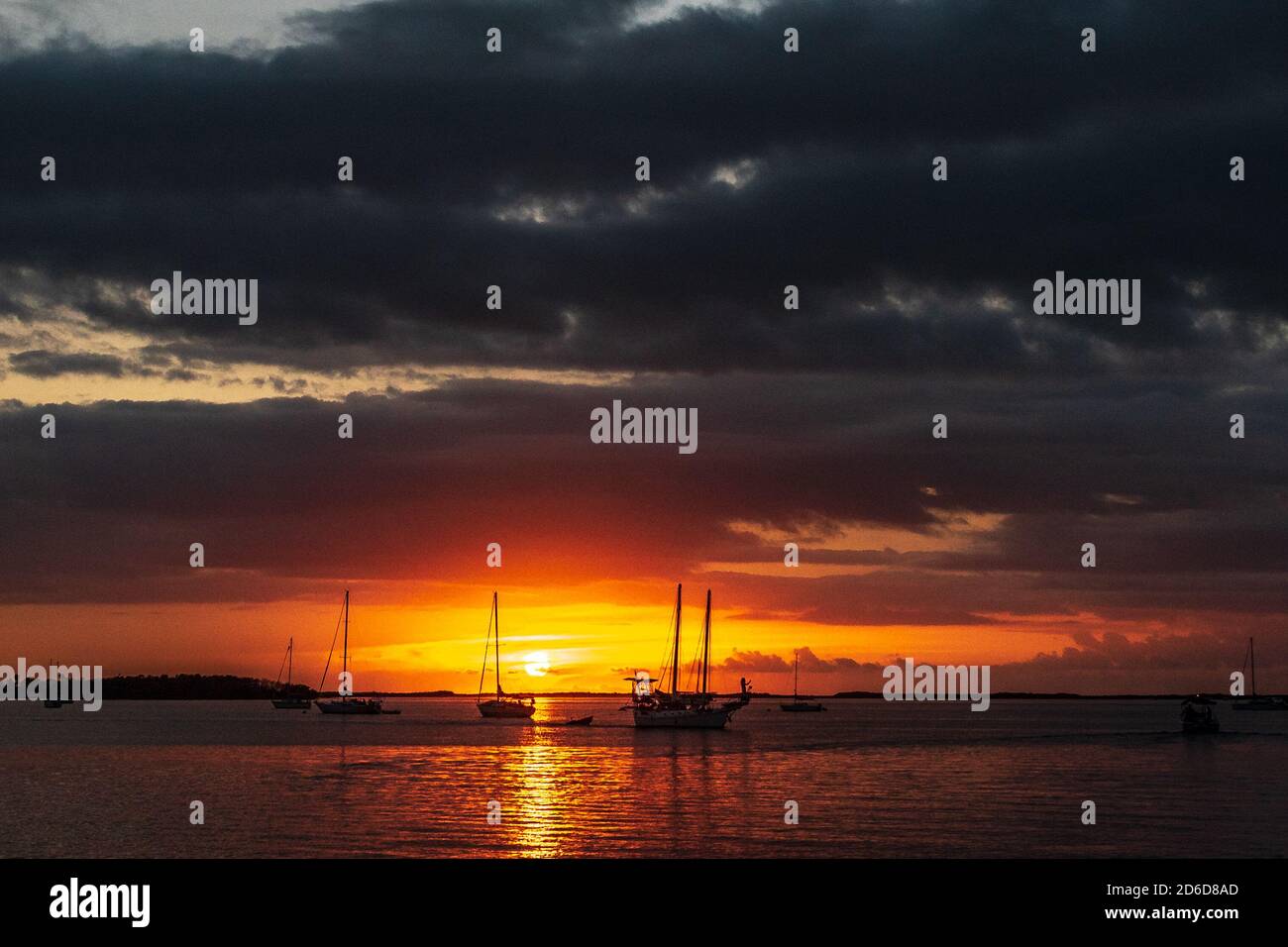 Il sole dorato si tramonta dietro le sagome delle barche sull'oceano E illuminare le nuvole sopra in Key Largo in Le Florida Keys Foto Stock