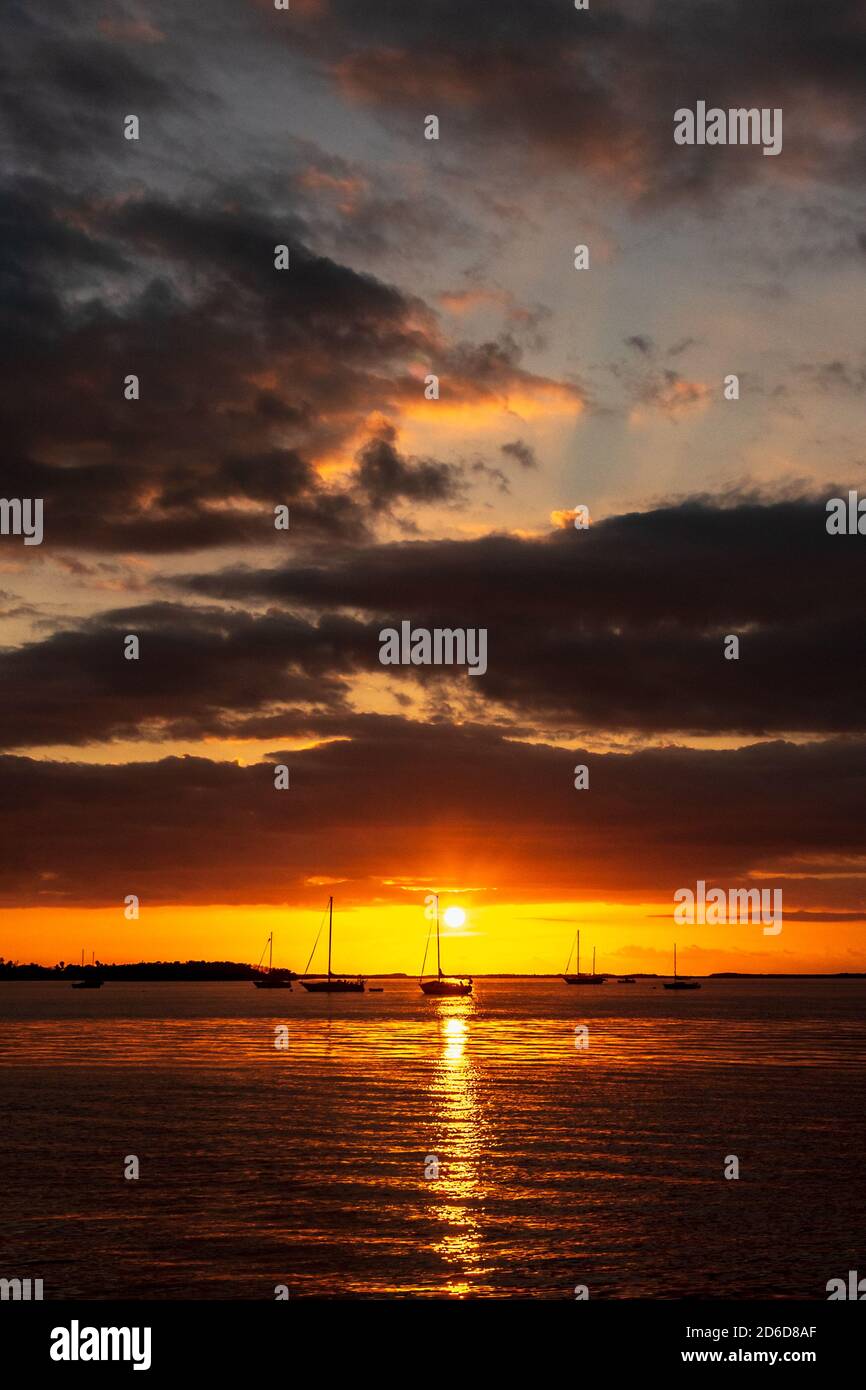 Il sole dorato si tramonta dietro le sagome delle barche sull'oceano E illuminare le nuvole sopra in Key Largo in Le Florida Keys Foto Stock