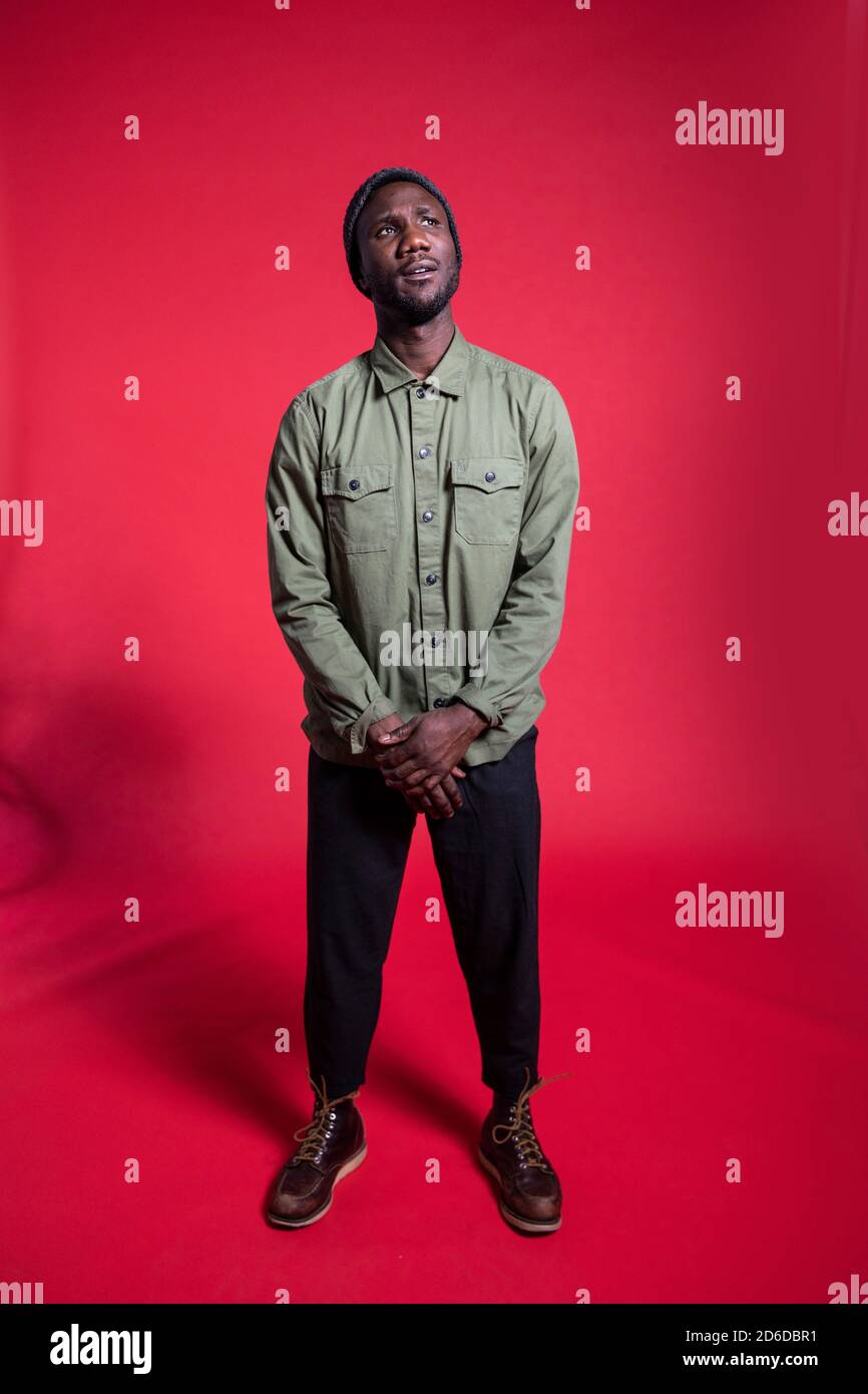 Ritratto di giovane uomo nero in piedi su sfondo isolato guardando verso l'alto. Lunghezza completa. Foto Stock