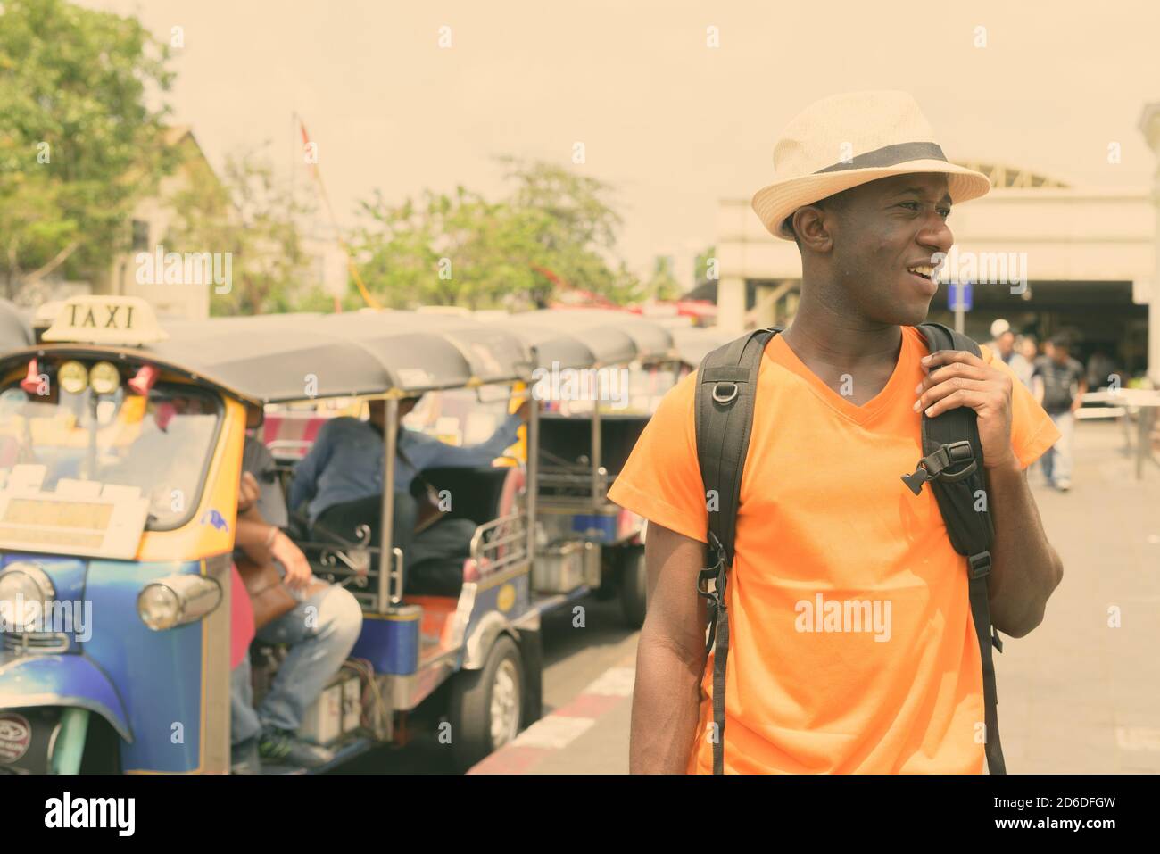 Giovani felici Africano nero tourist uomo sorridente mentre il pensiero e visite presso la stazione ferroviaria di Bangkok in Thailandia Foto Stock