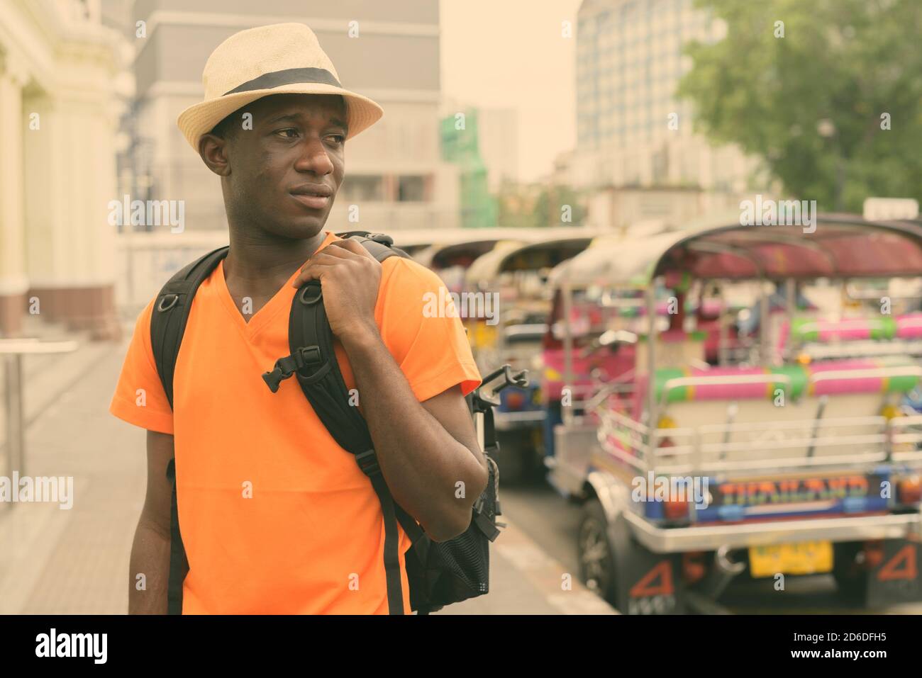 I giovani neri africani uomo turistica pensando mentre si tiene nello zaino e visite turistiche alla stazione ferroviaria con i tricicli parcheggio a Bangkok in Tailandia Foto Stock