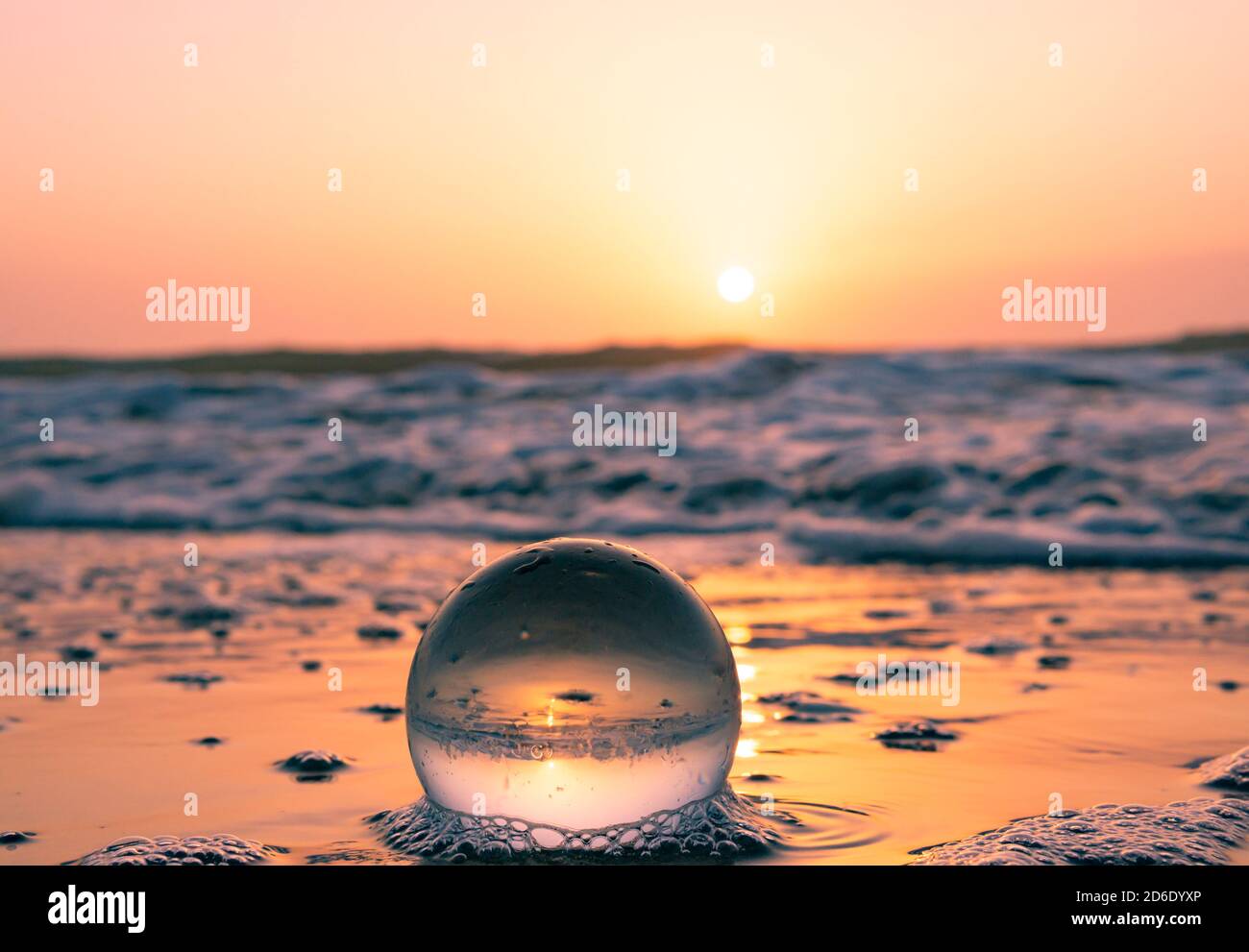 Bella palla di vetro calmante acqua sulla spiaggia di onde oceaniche a. tramonto colorato Foto Stock