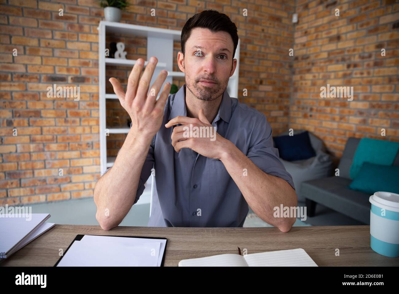 Ritratto dell'uomo che fa gesti a mano mentre si siede su di lui scrivania Foto Stock