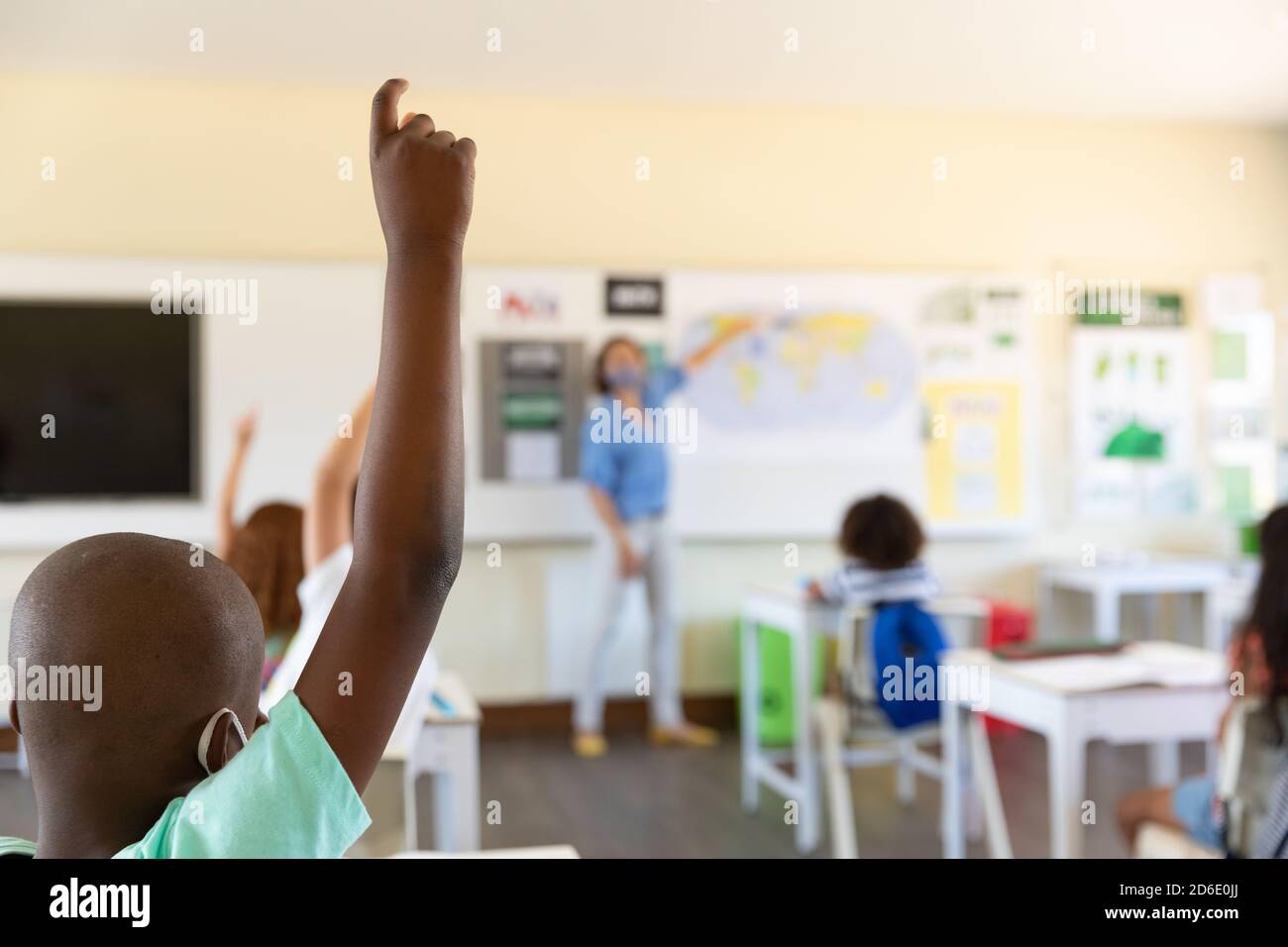 Studenti che alzano le mani in classe a scuola Foto Stock