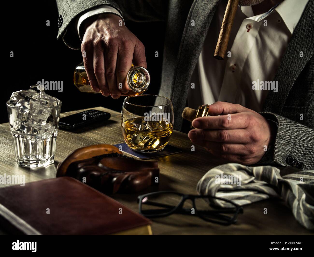 Uomo d'affari allevia lo stress dopo una dura giornata di lavoro bevendo whiskey Foto Stock