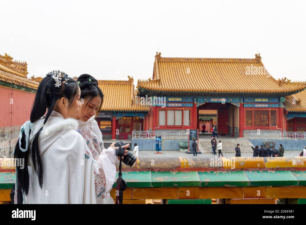 Pechino, Cina - Novembre 21 2019: Due giovani donne cinesi vestite con abiti tradizionali cinesi in tonalità bianche, rivisitano le fotografie che hanno tak Foto Stock