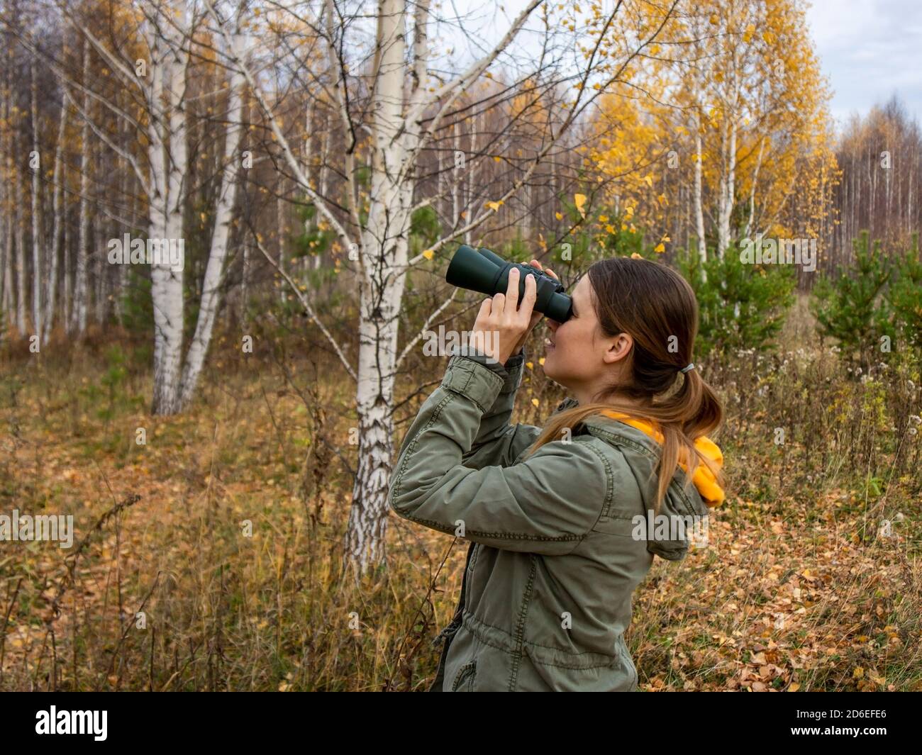 SONY DSCYoung birdwatcher donna con binocoli nella foresta autunnale. Birdwatching, zoologia, ecologia. Ricerca, osservazione di animali. Ornitologia Foto Stock