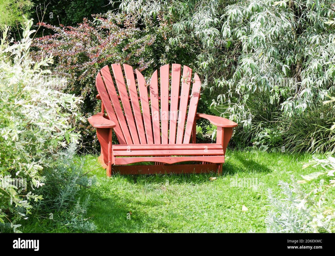 Sedia Adirondack a forma di cuore rosso in giardino Foto Stock