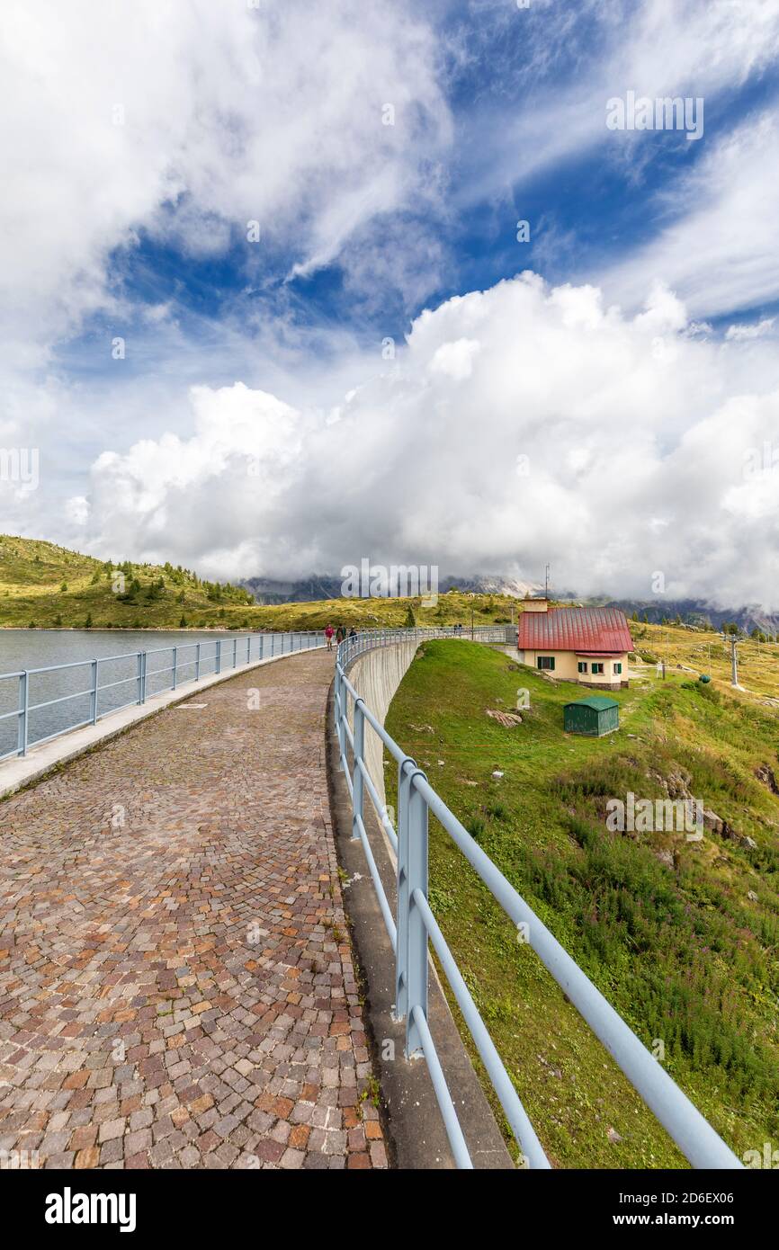 La passerella della diga di Cavia con il Lago del Cavia in un giorno di copertura, la casa del guardiano con il tetto rosso, falcade, belluno, veneto, Italia Foto Stock