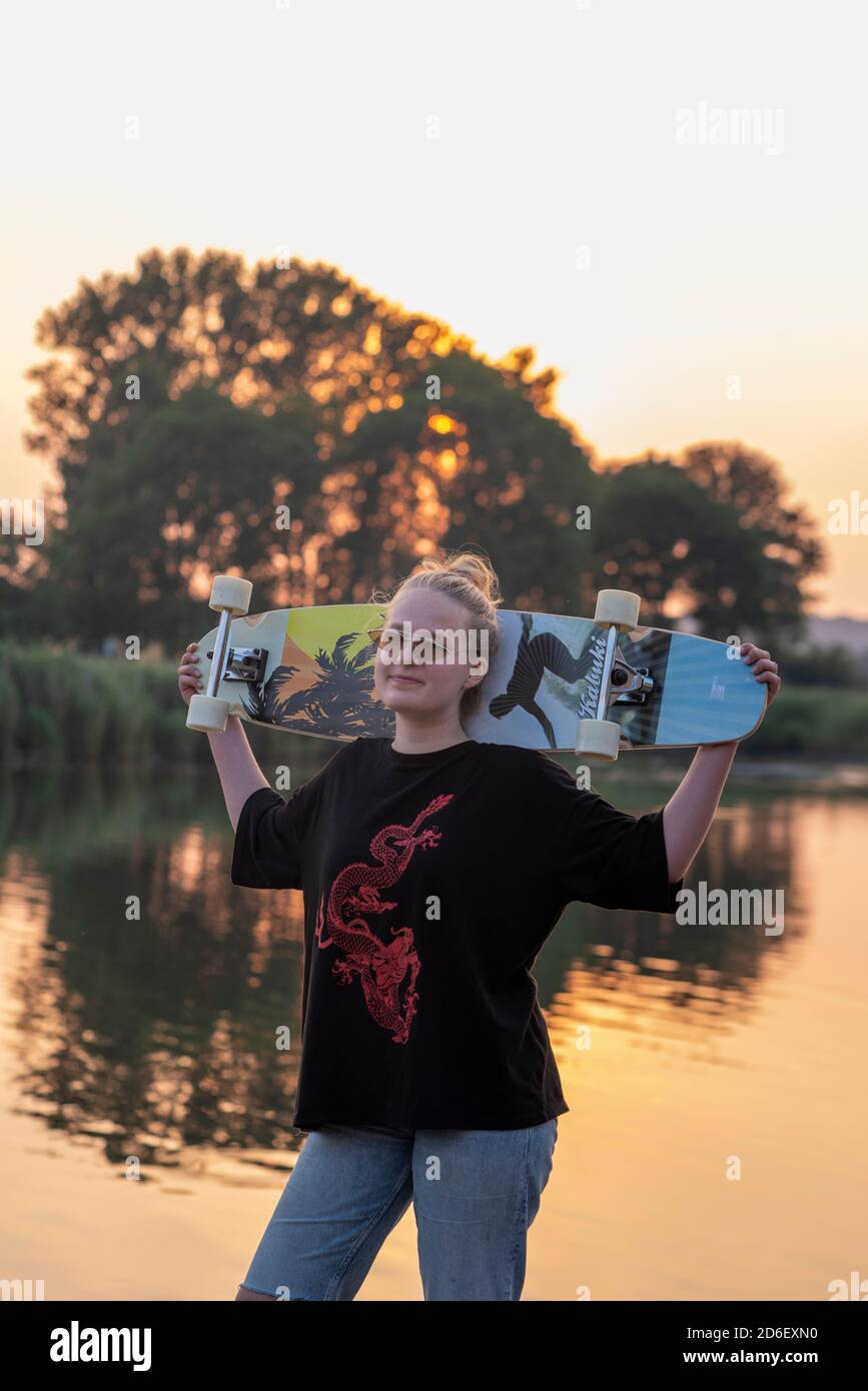 La ragazza si erge sul lago con un longbard al tramonto Foto Stock