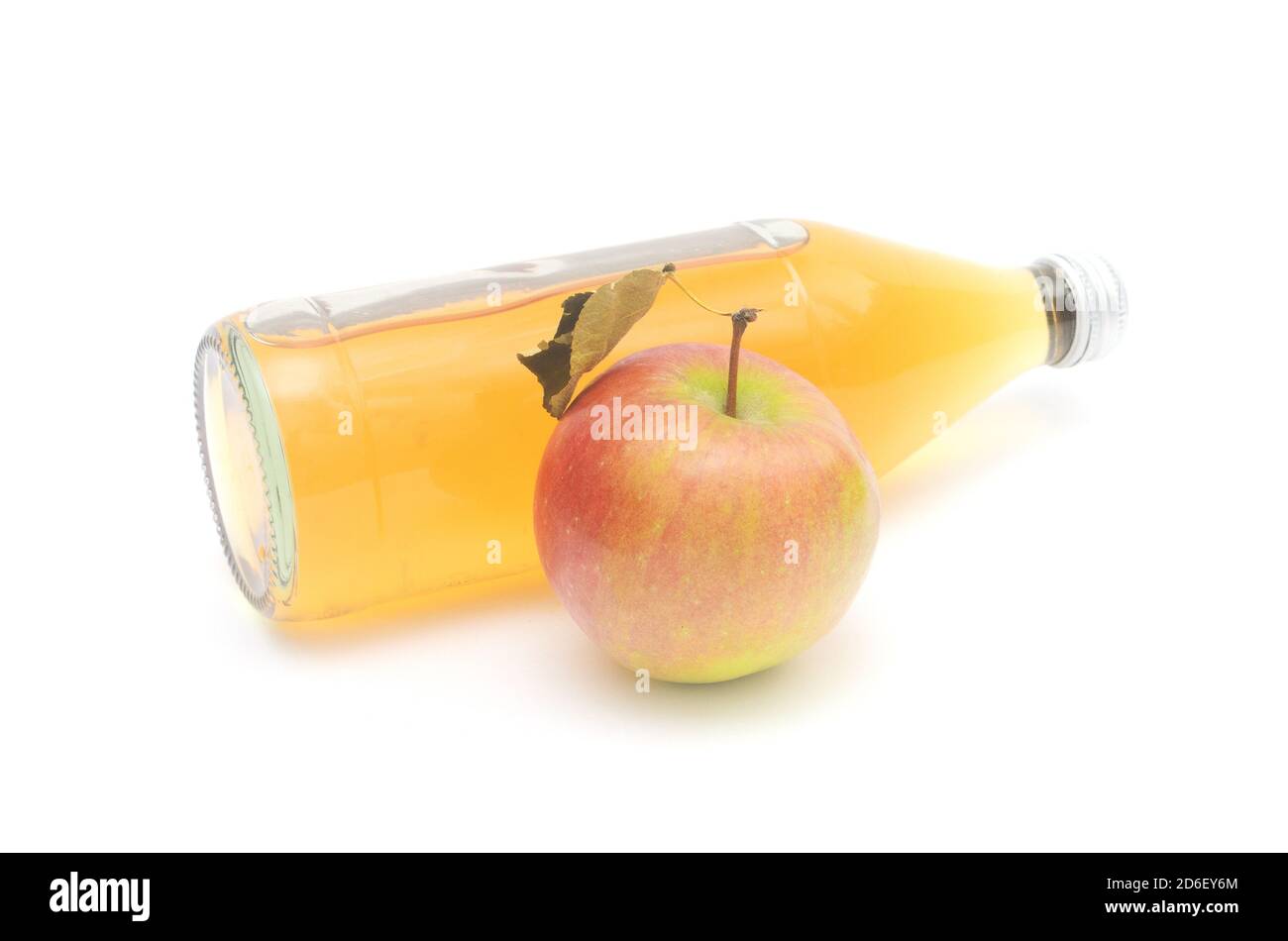 Una mela intera con foglia e una sdraiata bottiglia di aceto di sidro di mele isolato su fondo bianco. Foto Stock