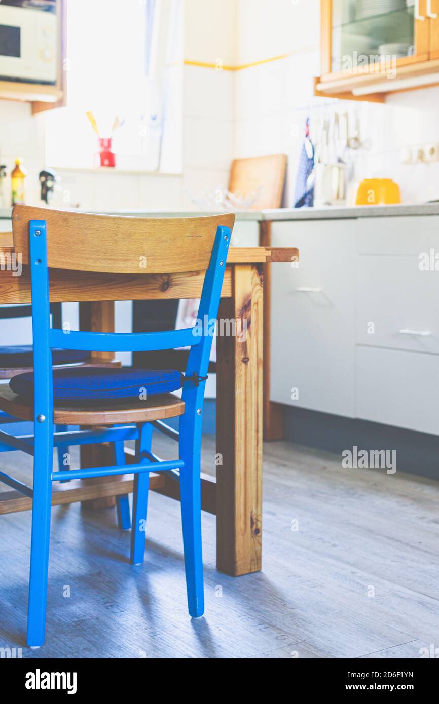 Vista interna - una sedia blu, un tavolo in legno in una piccola cucina in una casa. Foto Stock