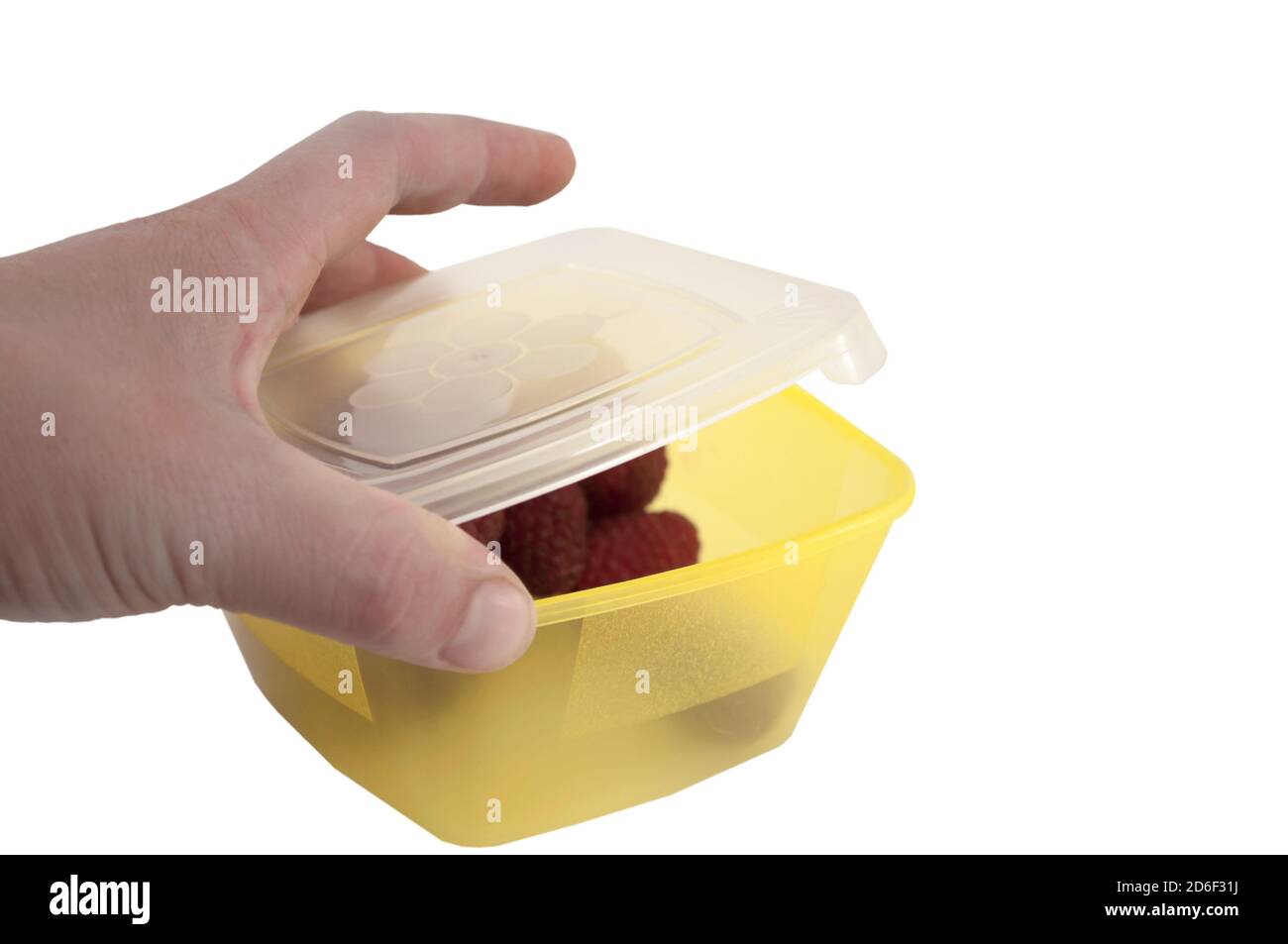 La mano femminile copre il coperchio di una scatola per il pranzo con lamponi, cibo sano sulla strada, isolato su uno sfondo bianco Foto Stock