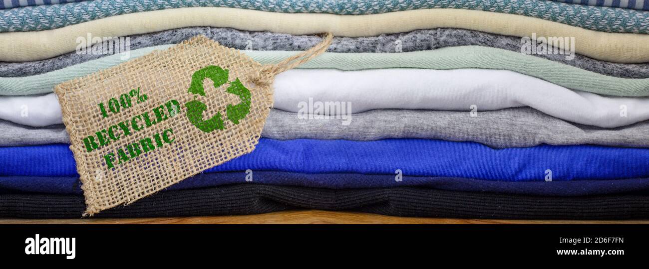 Riciclare l'icona dei vestiti sull'etichetta di tessuto con il 100% di testo riciclato. Intestazione banner di moda sostenibile ed etica dello shopping Foto Stock