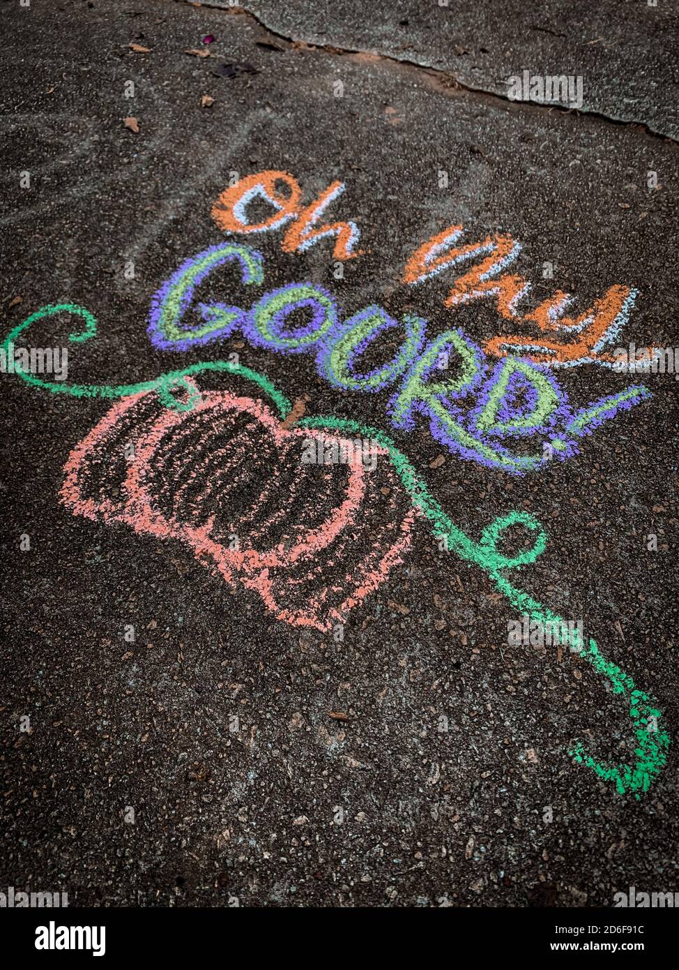 Coloratissima arte gessata autunnale su un vialetto che dice: "OH mio gourd!" con una zucca sotto. Foto Stock