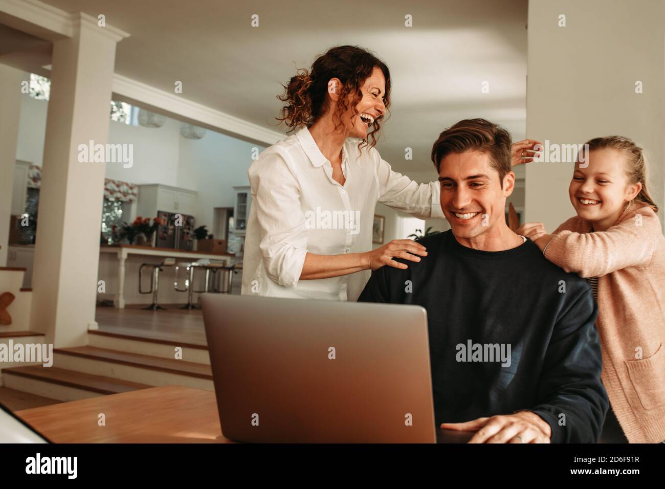 Uomo con la moglie e la figlia seduti davanti al computer portatile che effettua una videochiamata. La tua famiglia è felice di videochiamare mentre sei a casa. Foto Stock