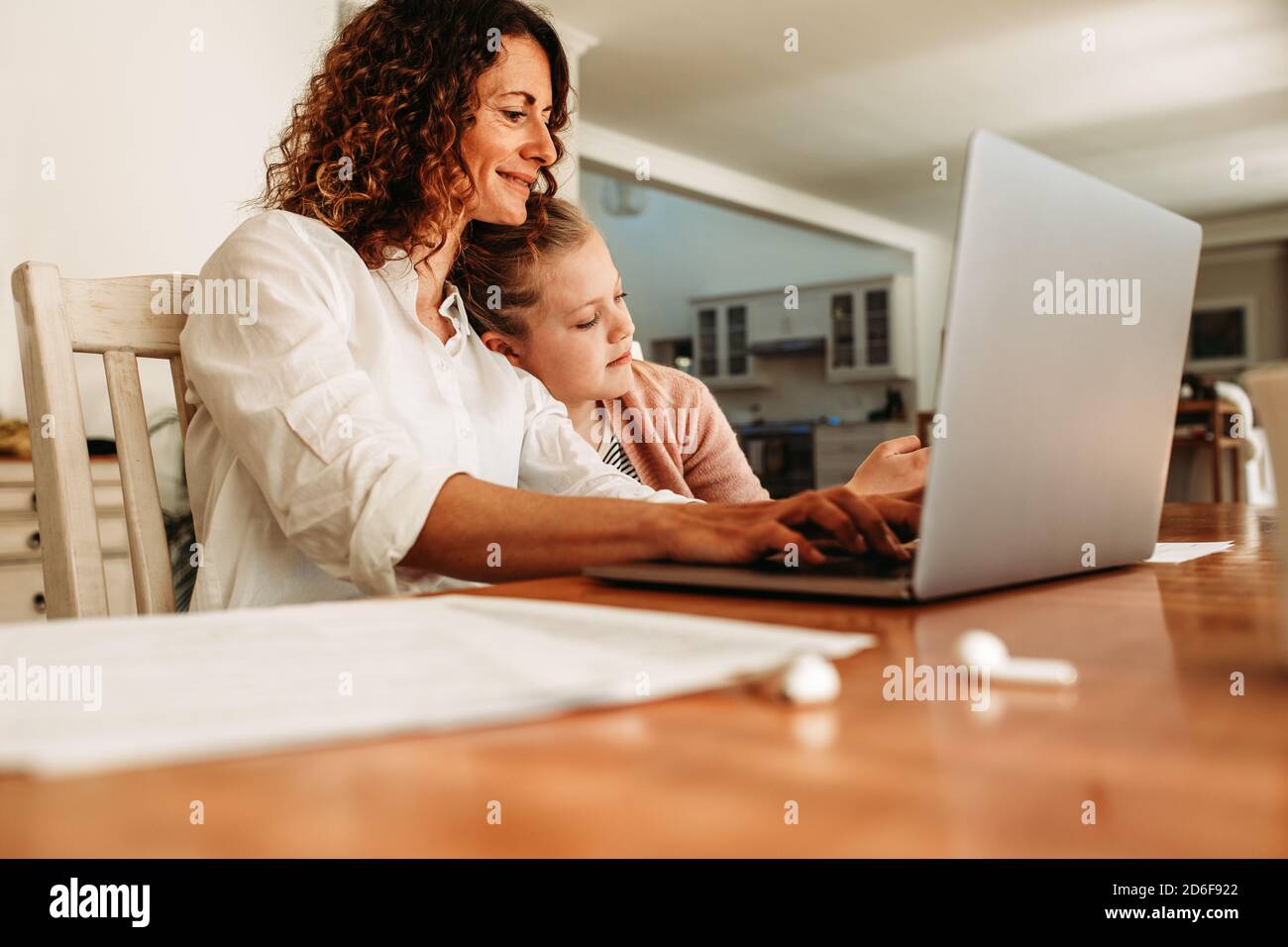 donna d'affari che lavora da casa con sua figlia seduta accanto. Donna che usa un notebook a casa. Foto Stock