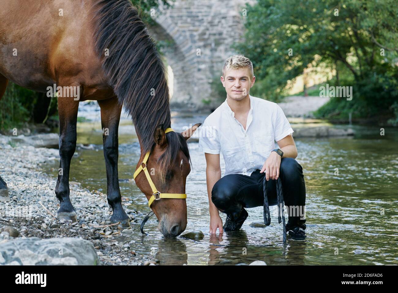 Ritratto di un giovane biondo con un cavallo un fiume Foto Stock