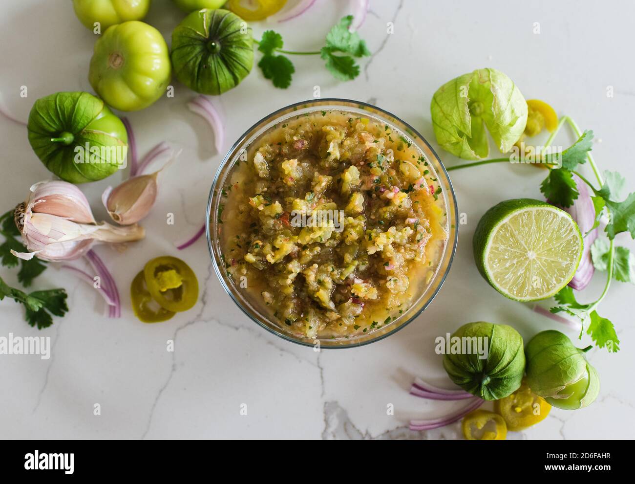 Testa di salsa di tomatillo ed è ingredienti su quarzo bianco. Foto Stock