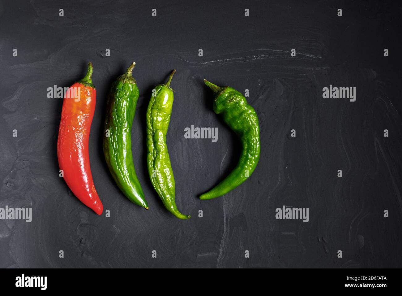 Peperoni caldi viziati su sfondo scuro. Cibo brutto. Spazio per il testo Foto Stock