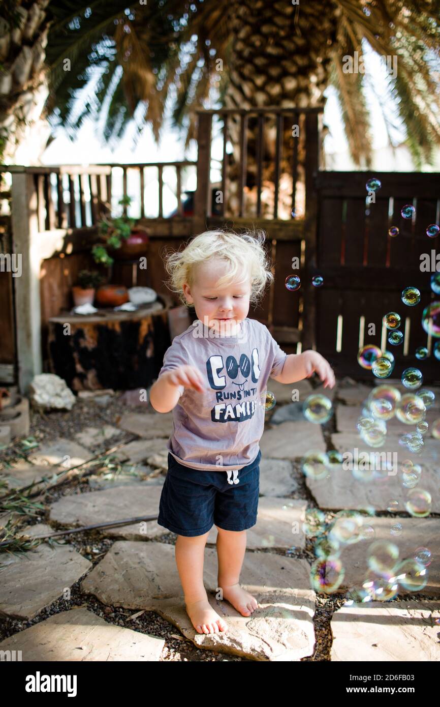 Ragazzo di due anni in piedi in Yard giocando con le bolle Foto Stock
