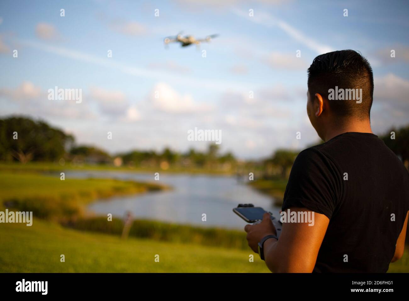 giovane che vola un drone nel parco in un tramonto Foto Stock