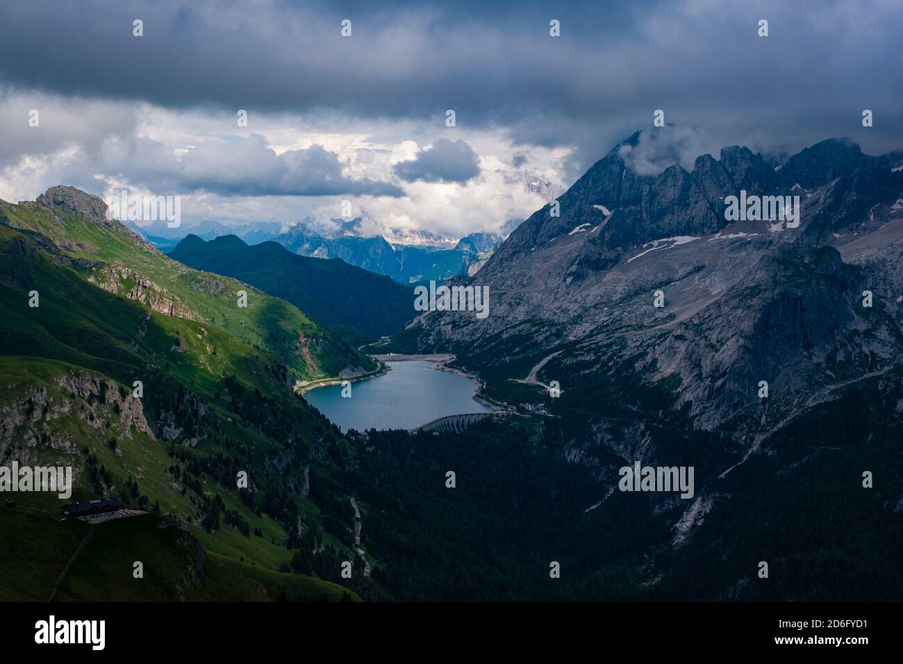 Vista del paesaggio montuoso delle dolomiti intorno al Lago di Fedaia, al Lago di Fedaia e alla cima della Marmolata, Marmolada coperta di nuvole. Foto Stock