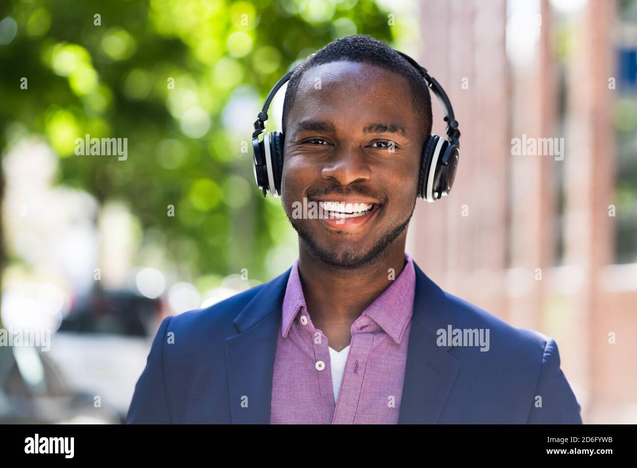 African American Man ascoltare musica su cuffie wireless all'esterno Foto Stock