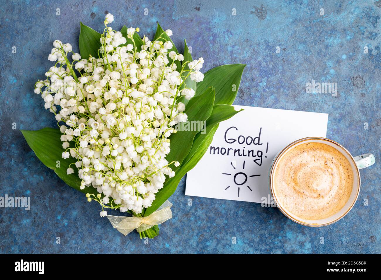 Note Buongiorno e tazza di caffè con bouquet di fiori giglio della valle su  sfondo blu. Colazione, caffè del mattino, carta, vista dall'alto Foto stock  - Alamy