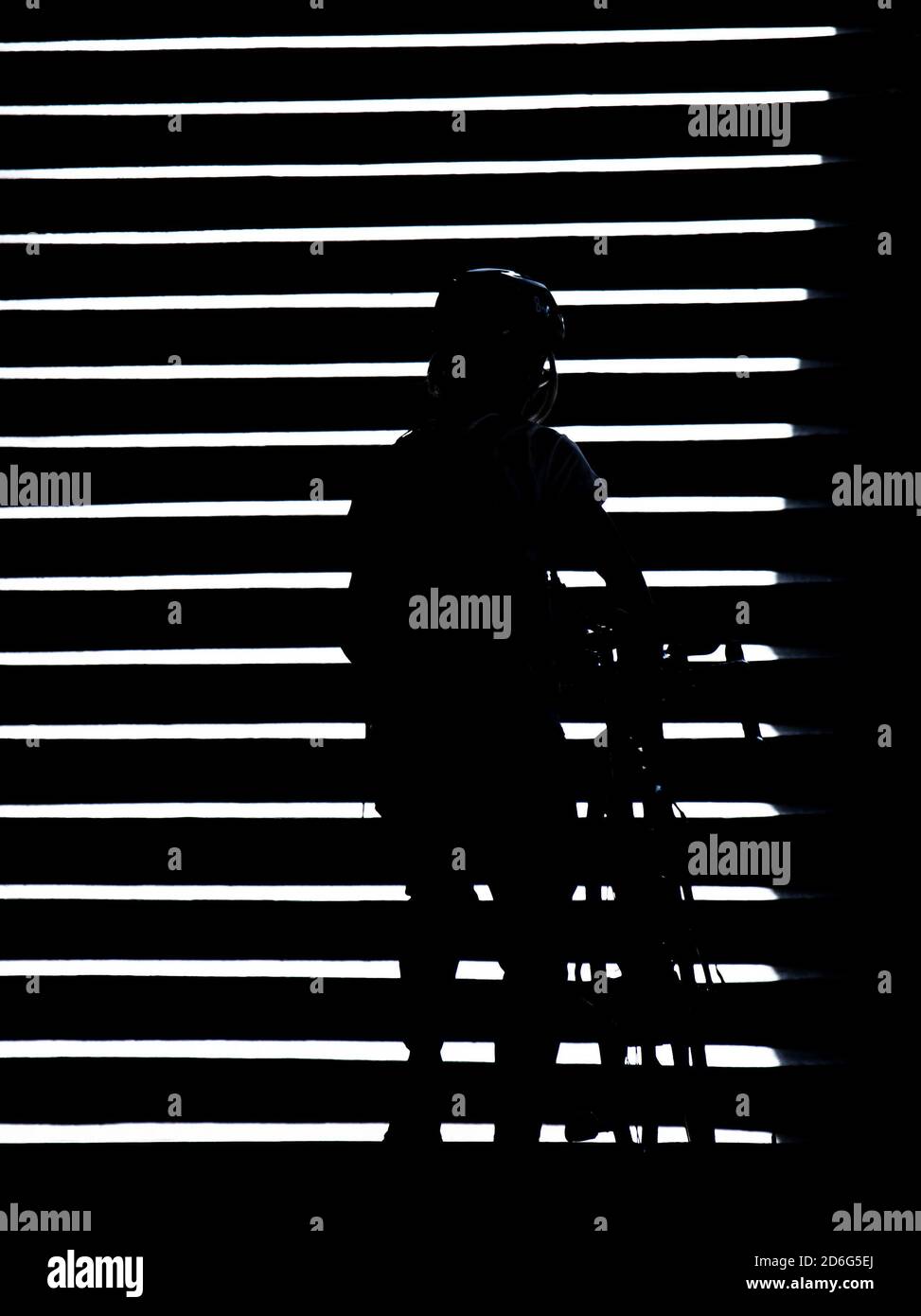 Silhouette ombra di una persona che spinge una bicicletta sulle scale all'aperto di notte, bianco e nero ad alto contrasto Foto Stock