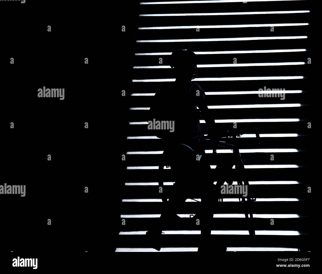 Silhouette ombra di una persona che porta una bicicletta sulle scale all'aperto di notte, bianco e nero ad alto contrasto Foto Stock
