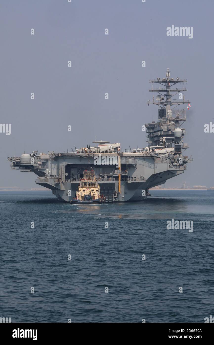 201007-A-RX269-1185 GOLFO DEL BAHRAIN (OTTOBRE 7, 2020) UNA barca da rimorchiatore Bahraini spinge la portaerei USS Nimitz (CVN 68) da est, incomiando ad una visita di manutenzione e logistica a Khalifa bin Salman Port, Bahrain, 7 ottobre. Nimitz, il fiore all'occhiello del Nimitz Carrier Strike Group, è schierato nell'area operativa della 5a flotta degli Stati Uniti, conducendo missioni a sostegno dell'OIR, e operazioni di sicurezza marittima a fianco di partner regionali e di coalizione. (Foto dell'esercito degli Stati Uniti di SPC. William Gore) Foto Stock