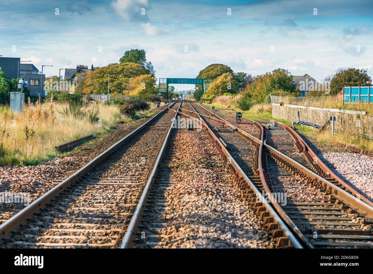 Binari ferroviari che viaggiano all'orizzonte e un ponte pedonale, vicino a Carnoustie, Scozia, Regno Unito Foto Stock