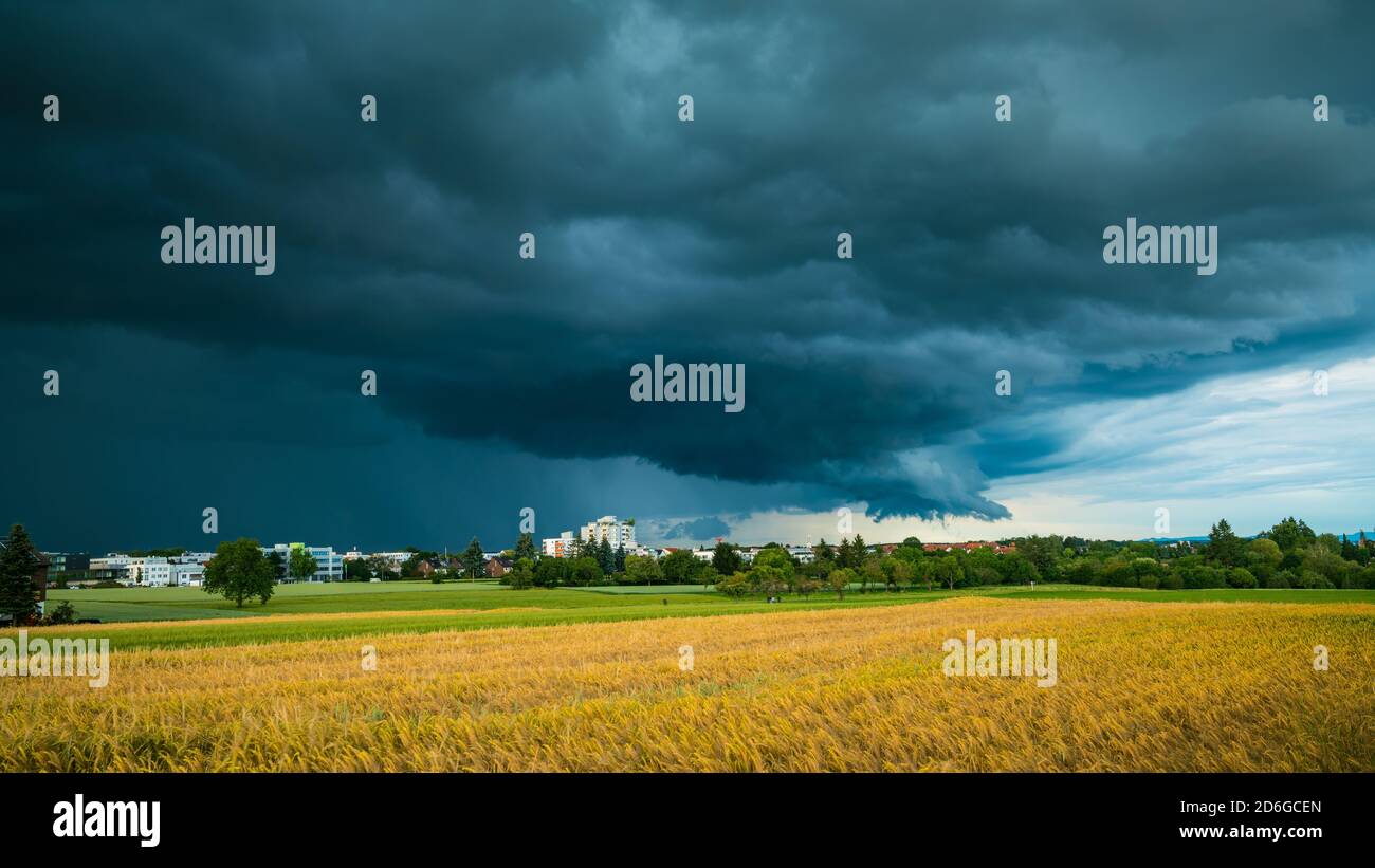 Germania, Stoccarda, cielo scuro drammatico di un fronte di tempesta pesante e temporale sopra il villaggio e i campi in estate Foto Stock