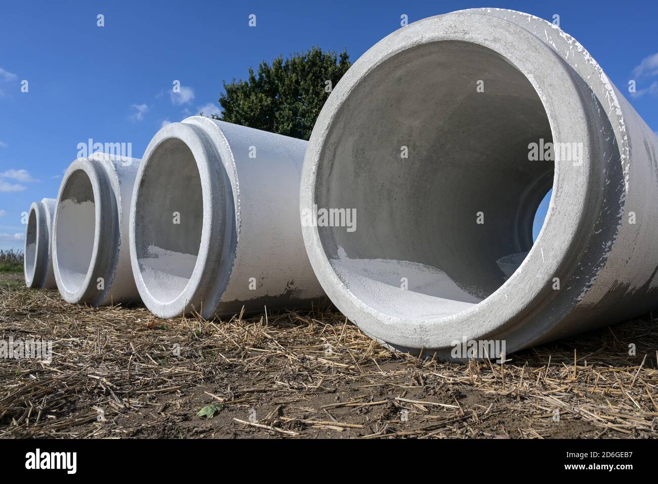 Grandi tubi d'acqua da cemento che si trovano fianco a fianco su un cantiere per costruire un sistema fognario di drenaggio contro l'allagamento, copia spazio, selezionato foc Foto Stock