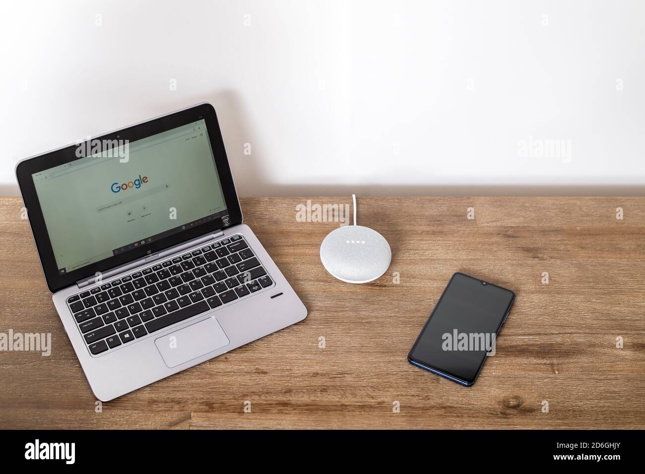Adelaide, Australia - 7 luglio 2019: Google Home Mini con computer portatile HP con Windows 10 e telefono cellulare impostato sul tavolo accanto l'uno all'altro Foto Stock