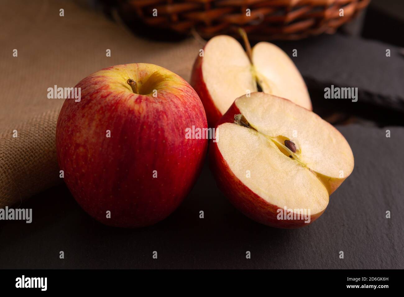 due mele rosse poste su un pezzo di ardesia dentro un ambiente poco luminoso Foto Stock